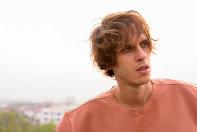 Portrait of young man looking away against sky