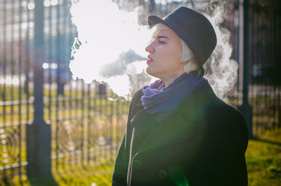 Young woman smoking while standing at park
