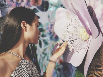 Young woman looking at artificial flower