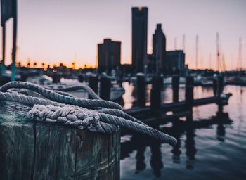 Close-up of rope tied to wooden post at harbor during sunset
