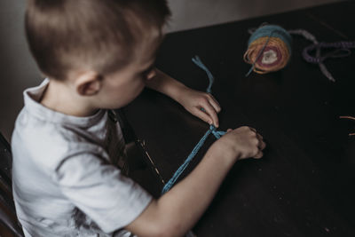 Young boy knitting with fingers at home during isolation