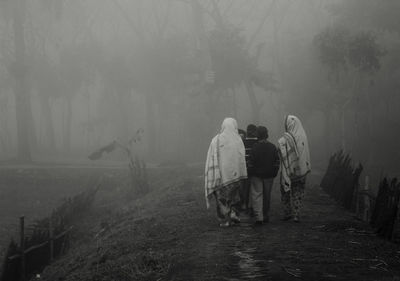 Rear view of people walking on road in forest