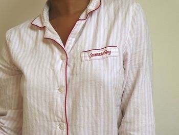 Midsection of woman wearing nightwear standing against wall