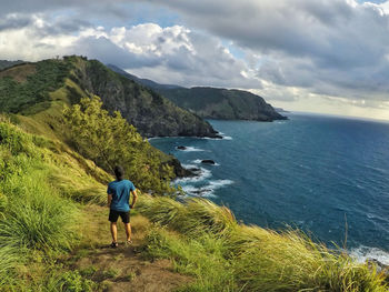 Man standing on mountain by sea against sky