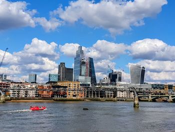 Buildings by river against cloudy sky