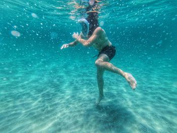 Young man wearing scuba mask swimming underwater in sea