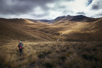 Rear view of man standing on mountain against sky