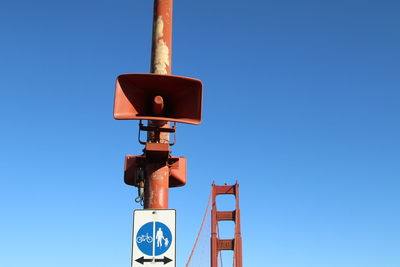 Low angle view of megaphone speakers against golden gate bridge