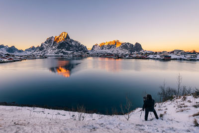 Rear view of person standing on snowcapped mountain against sky