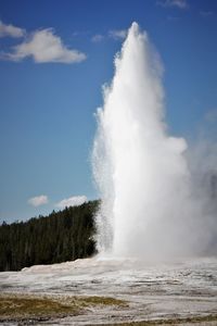 Waves splashing on shore against sky