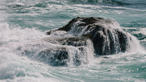 Impressive swell of wave washing onto rocks on storm day