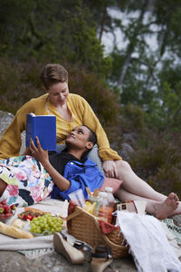 Female couple having picnic and reading book
