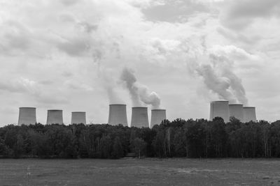 Smoke emitting from factory against sky