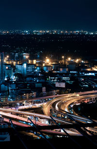 High angle view of illuminated street amidst buildings in city at night