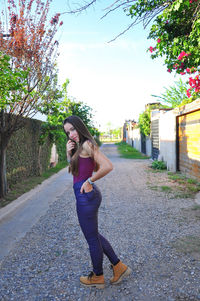 Full length portrait of young woman standing on road