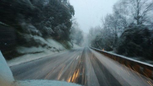 Road amidst trees against sky during winter
