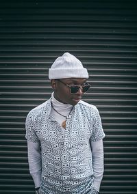 Man wearing sunglasses standing against wall