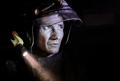 Portrait of man holding cigarette against black background