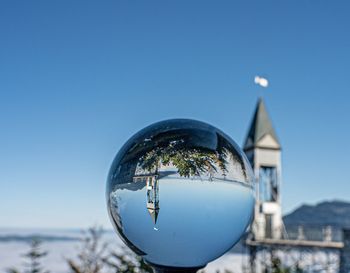 Close-up of crystal ball against blue sky