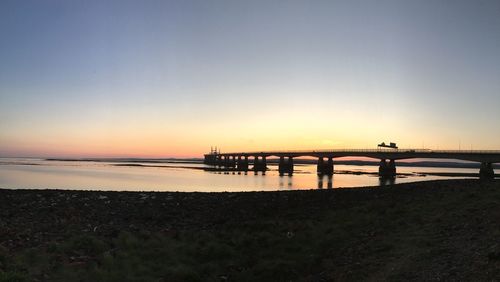 Silhouette pier over sea against sky during sunset