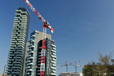 Low angle view of crane at construction site against sky