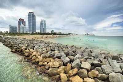 Rocks on beach by sea against sky