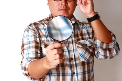 Portrait of man holding camera over white background