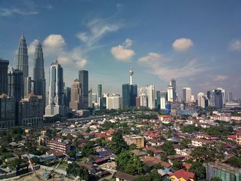 Aerial view of buildings in city against cloudy sky