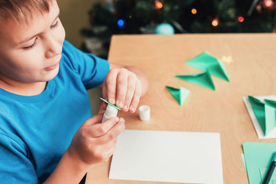 Midsection of boy holding paper while sitting on table