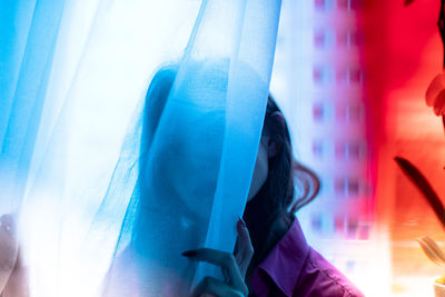 Portrait of woman against blue sky seen through window