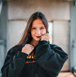 Portrait of smiling woman standing against wall