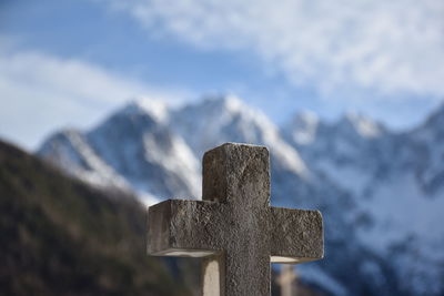 Close-up of cross shape against snowcapped mountain