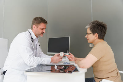 Side view of young man using laptop at clinic