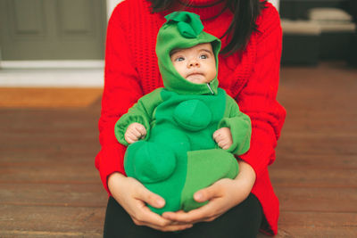 Midsection of mother with cute son sitting on hardwood floor at home