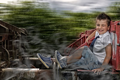 Portrait of cheerful boy winking while sitting on train