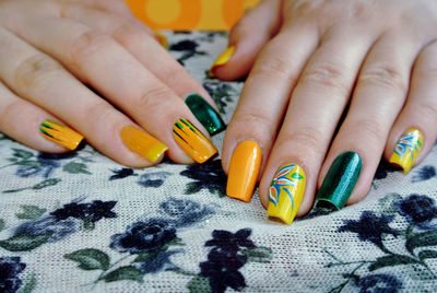 Close-up of woman with colorful fingernails on table