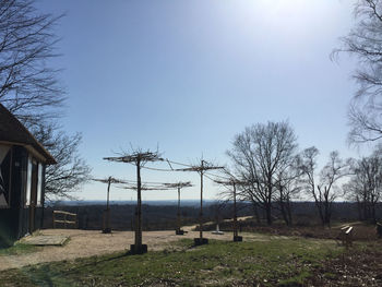 Bare trees by buildings against clear sky