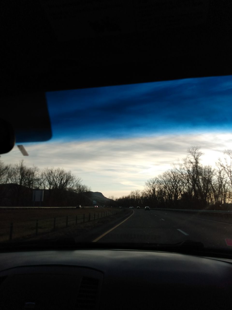 ROAD BY TREES SEEN THROUGH CAR WINDSHIELD