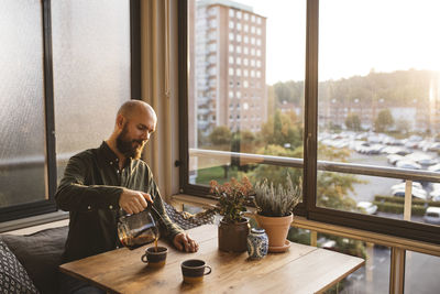 Man looking through window while sitting on table