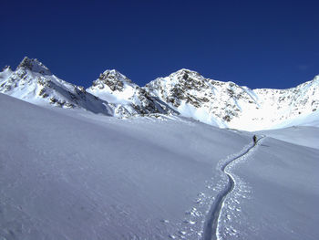 Scenic view of snow covered mountains against blue sky