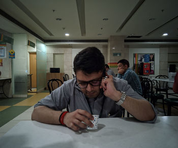 Young man looking down while sitting on table