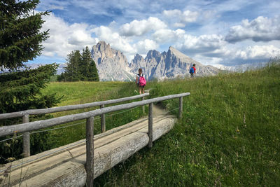 Wooden footbridge at seiser alm with sassolungo mountain group in front of blue sky with clouds