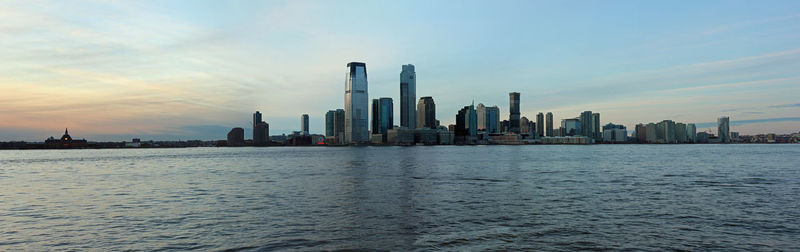 Sea and buildings against sky during sunset