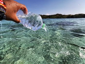 Midsection of person holding sea against sky