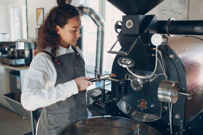 Side view of young woman working in factory