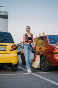 Shopping, sale concept. young stylish blonde woman with many shopping bags and coffee go to her car 