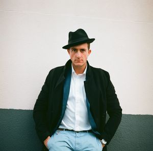 Portrait of young man sitting against wall