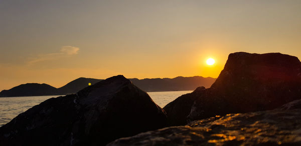 Scenic view of sea and mountains against sky during sunset