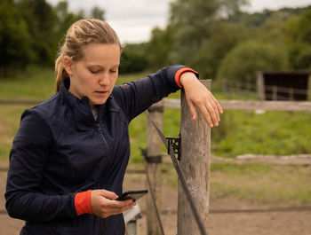 Man holding mobile phone while standing on field