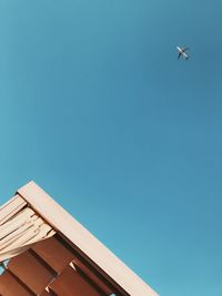 Low angle view of airplane flying against clear blue sky